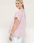Woman wearing a pink and white striped shirt against a plain background