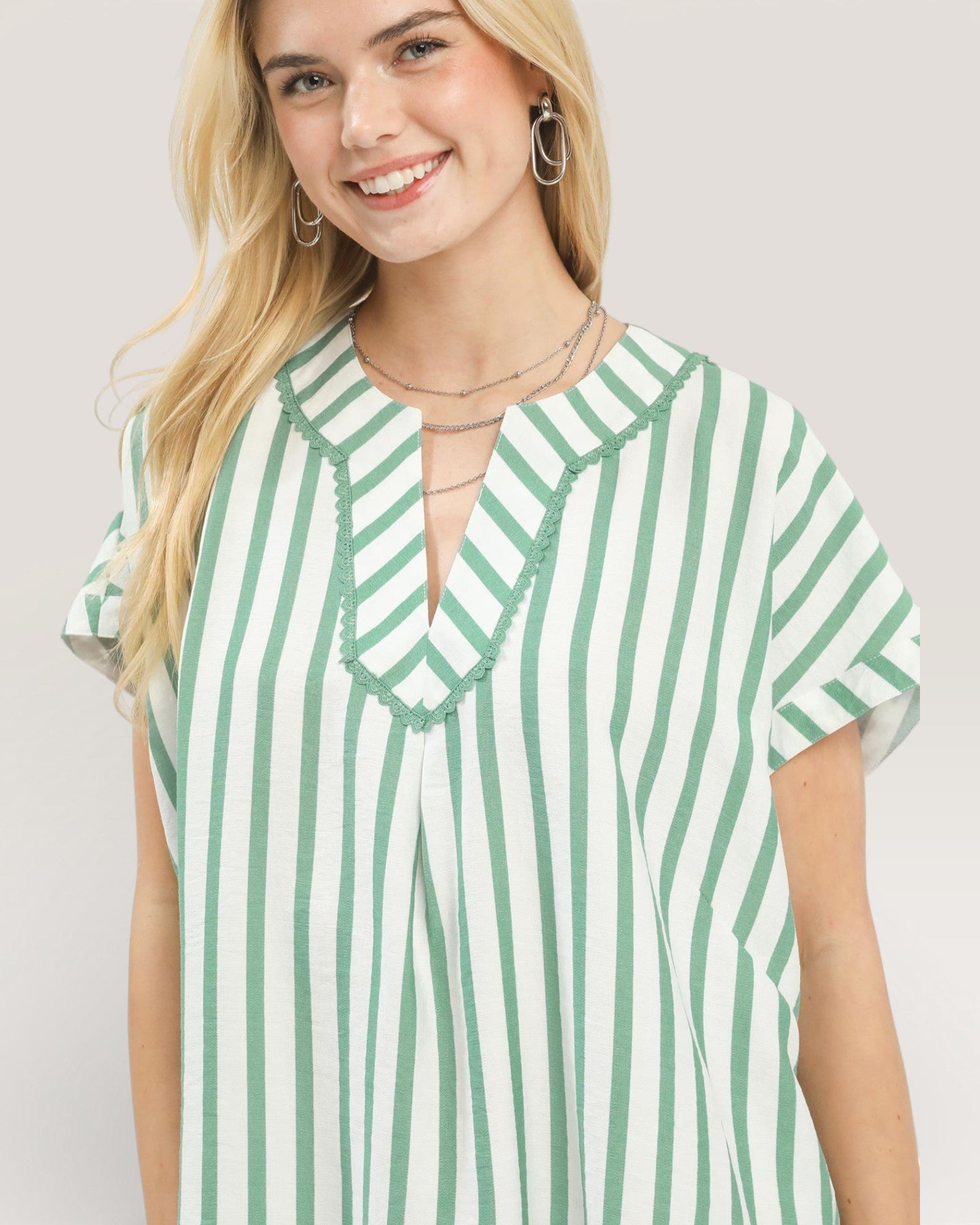 Woman wearing a green and white striped shirt against a plain background