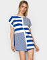Woman wearing a blue and white striped romper with on a plain background