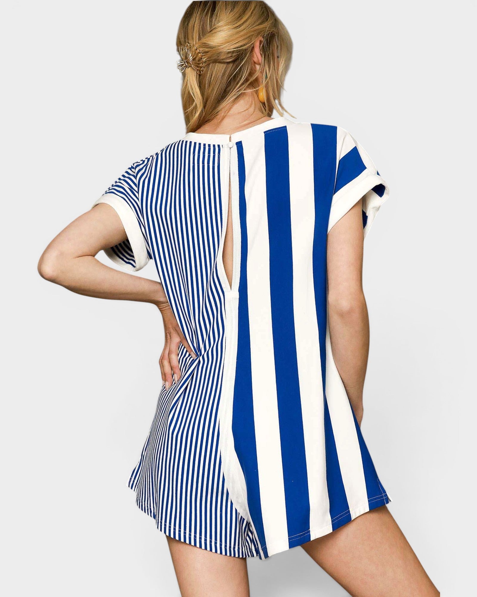 Woman wearing a blue and white striped romper with on a plain background