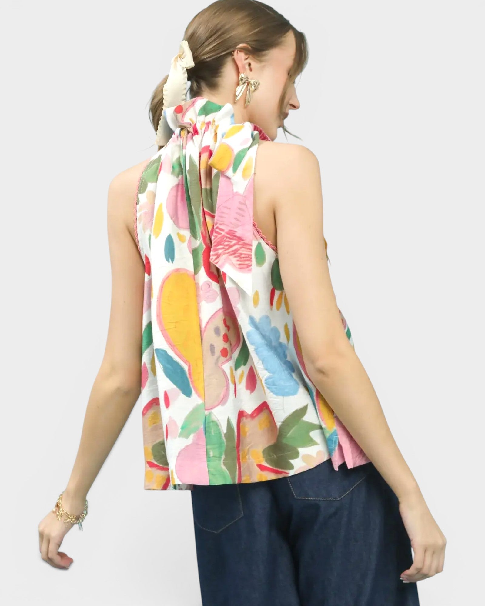 Woman wearing a colorful sleeveless top with floral pattern on a white background