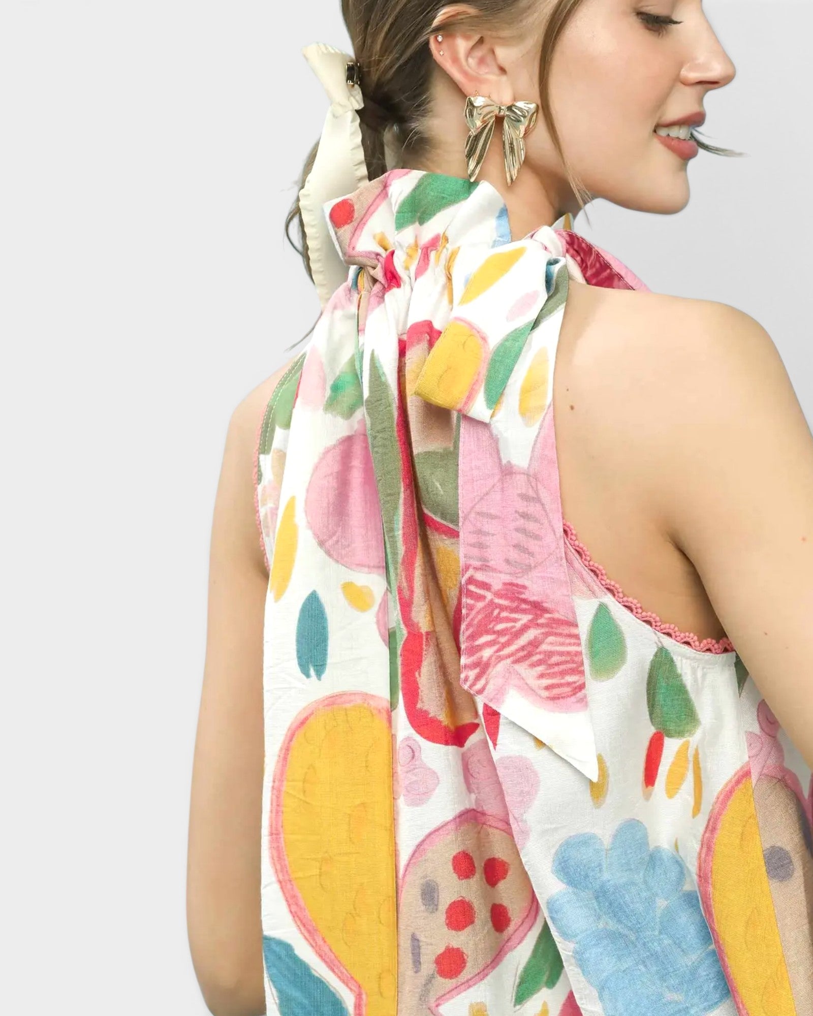Woman wearing a colorful blouse with abstract patterns on a plain background