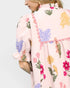 Woman wearing a light pink floral kimono-style garment on a plain background