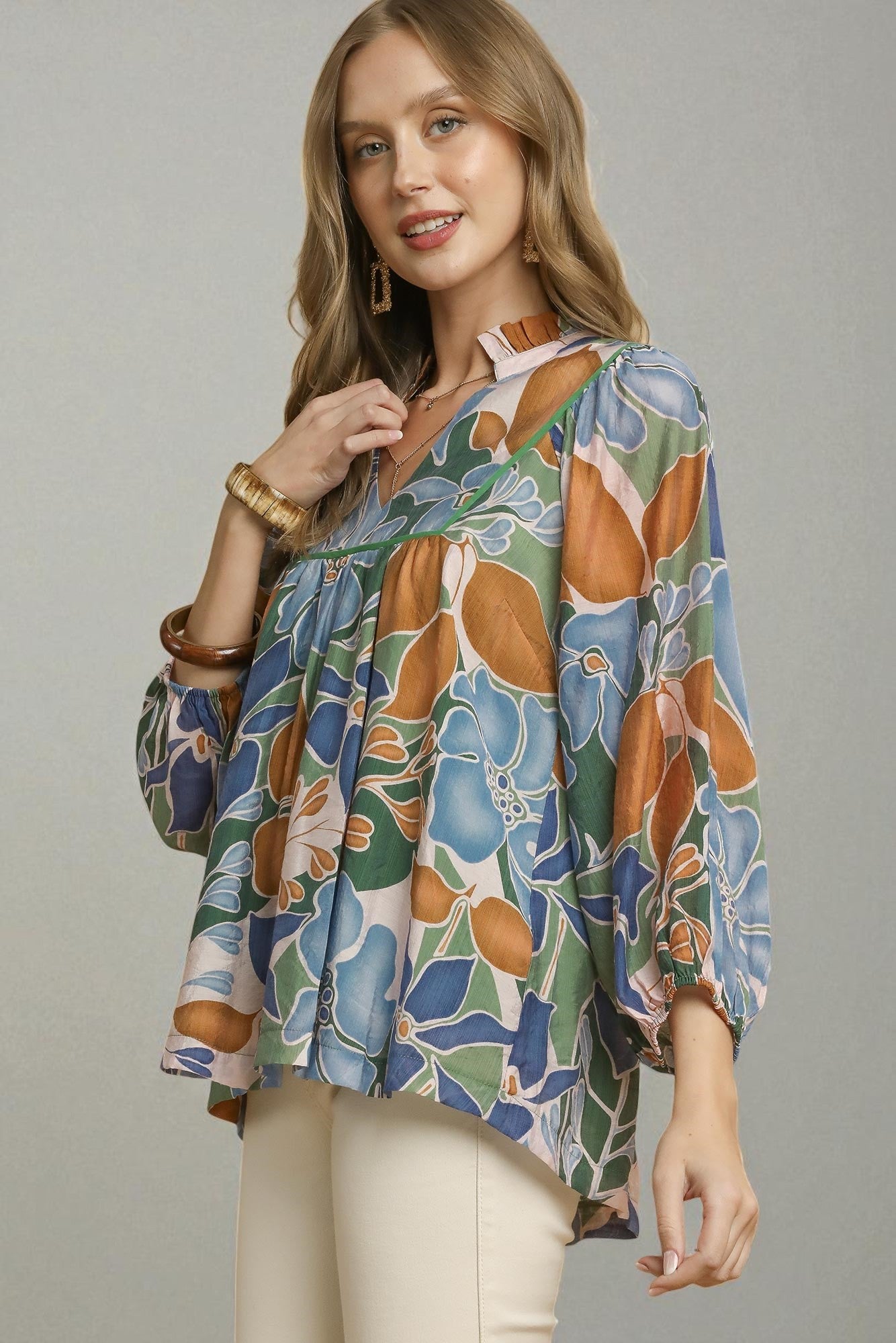 Woman wearing a colorful floral blouse against a gray background