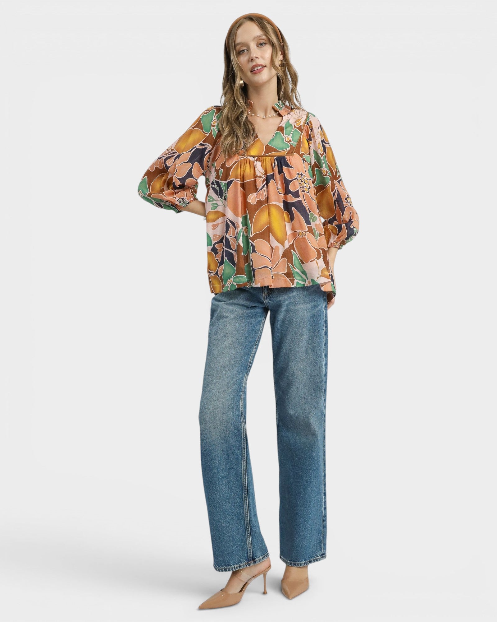 Woman wearing a colorful floral blouse and blue jeans on a white background