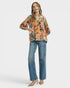 Woman wearing a colorful floral blouse and blue jeans on a white background