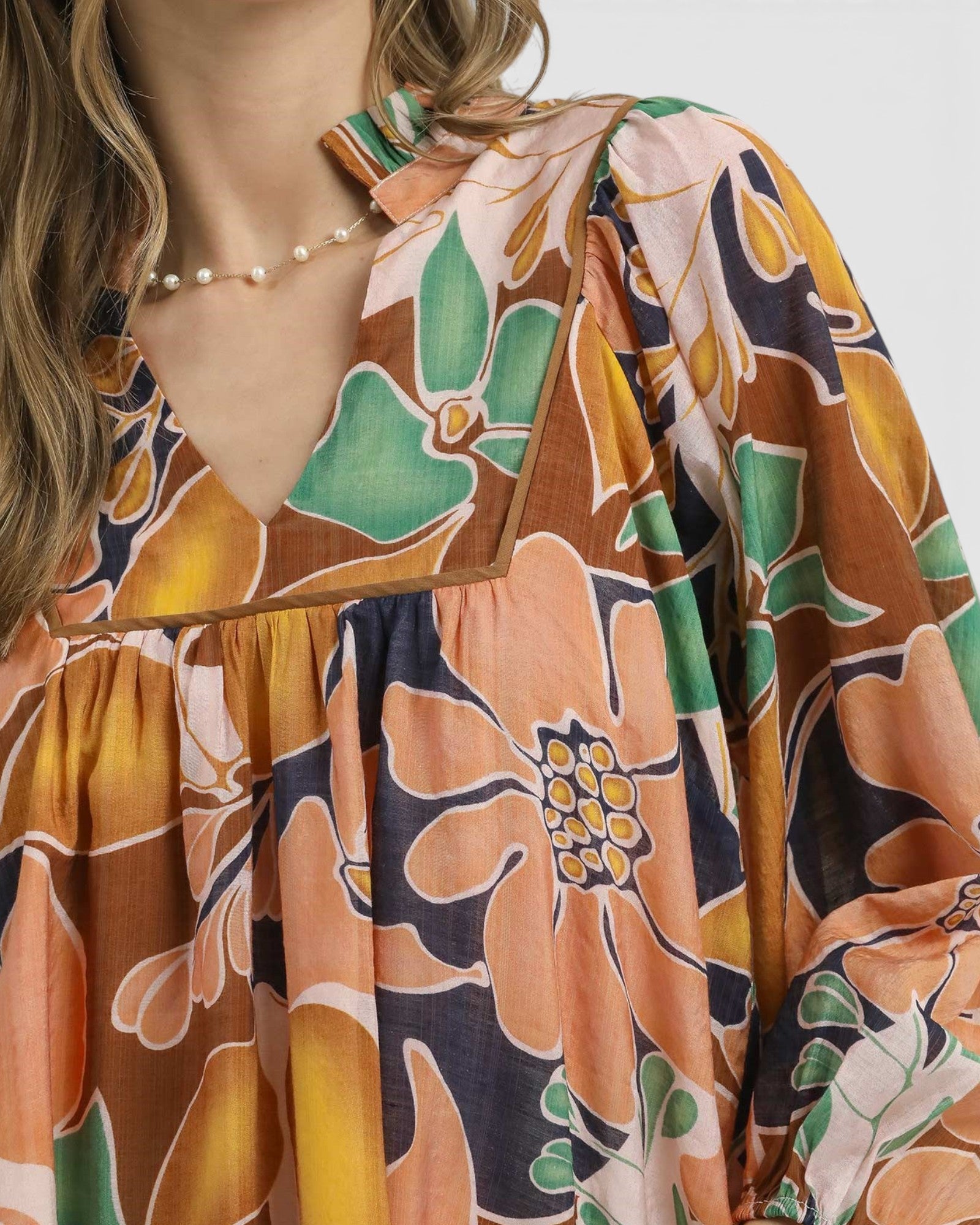 Close-up of a person wearing a floral blouse with a neutral background