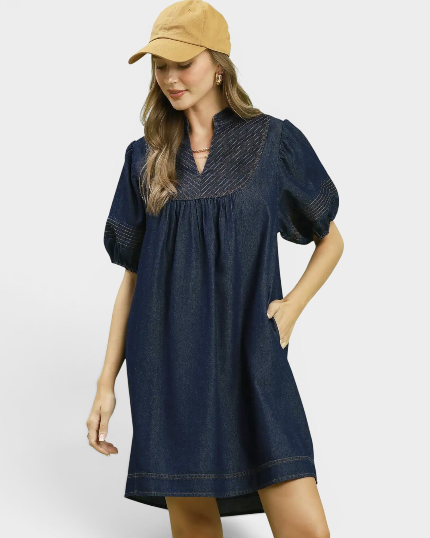 Woman wearing a blue dress and beige cap on a white background