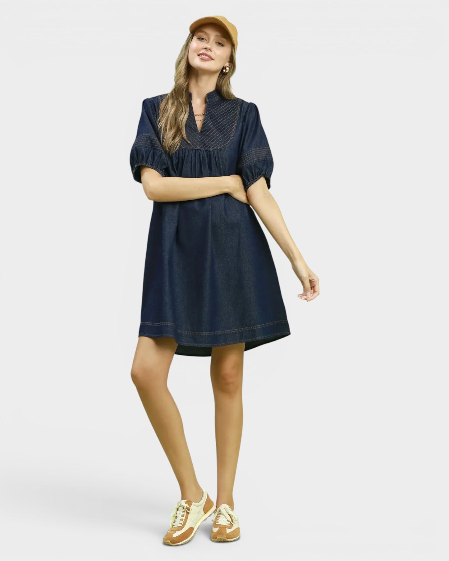 Woman wearing a navy dress with puff sleeves on a light gray background