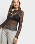 Woman wearing a sheer black lace top with long sleeves on a white background