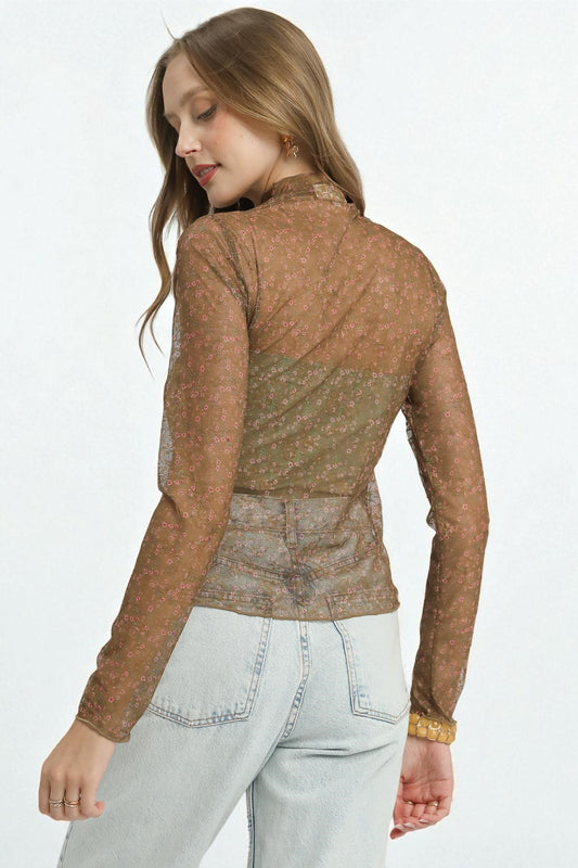 Woman wearing a brown patterned long-sleeve top and light blue jeans on a white background