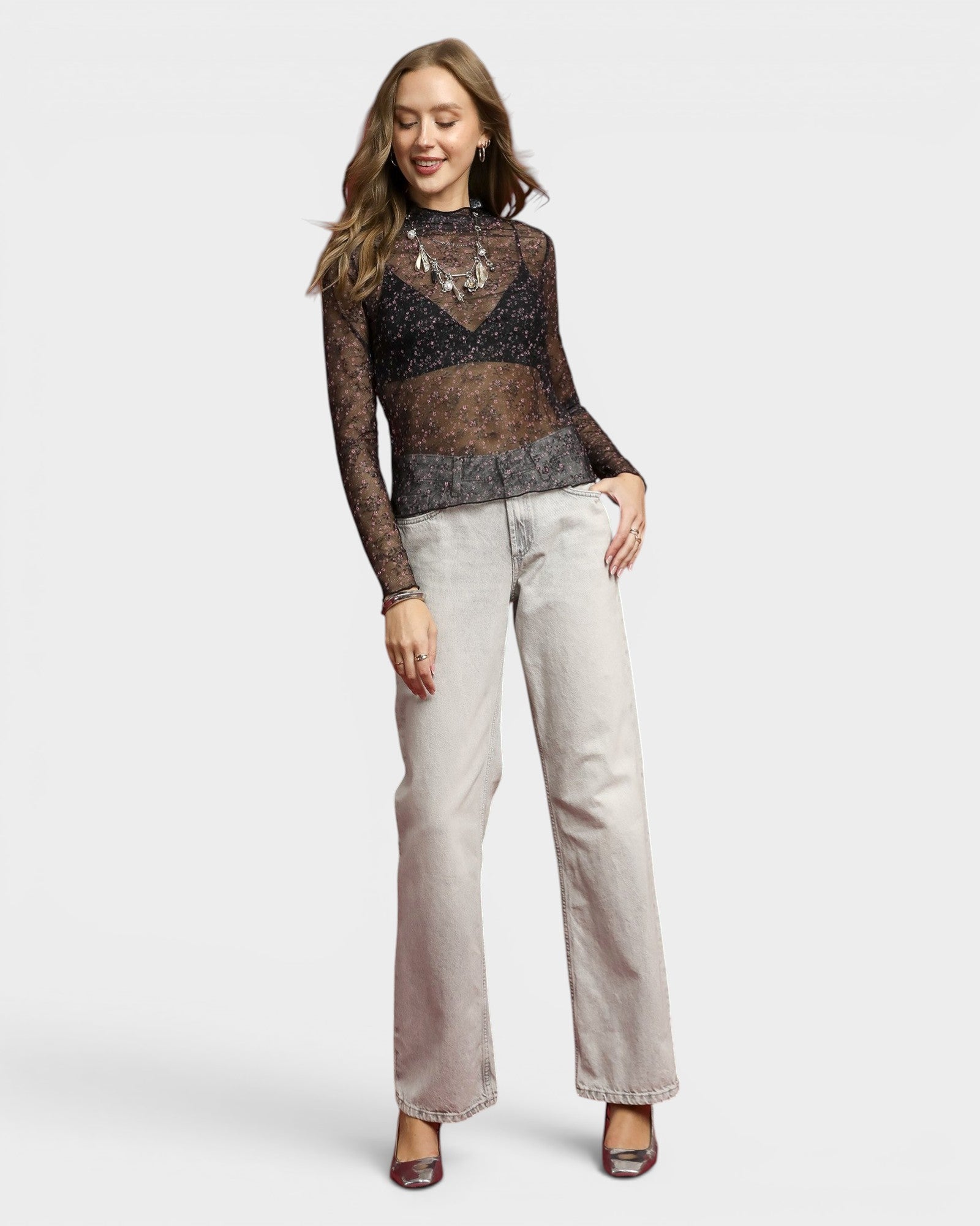 Woman wearing a patterned top and light-colored pants on a white background