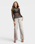 Woman wearing a patterned top and light-colored pants on a white background