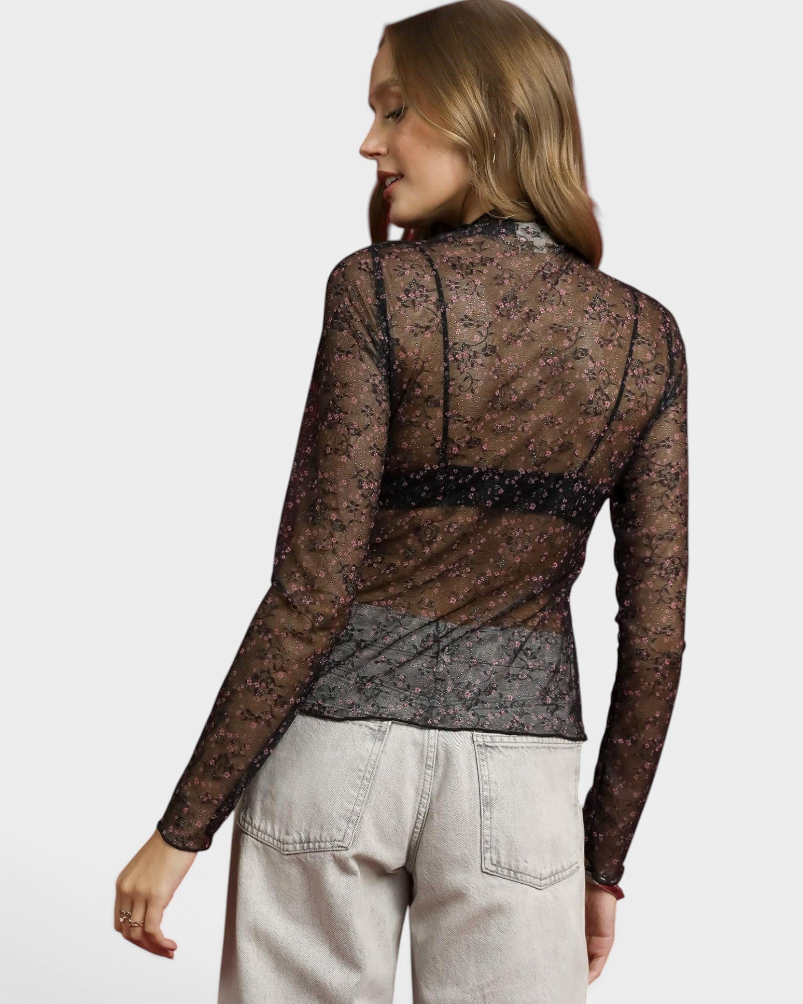 Woman wearing a sheer black lace top with a plain background