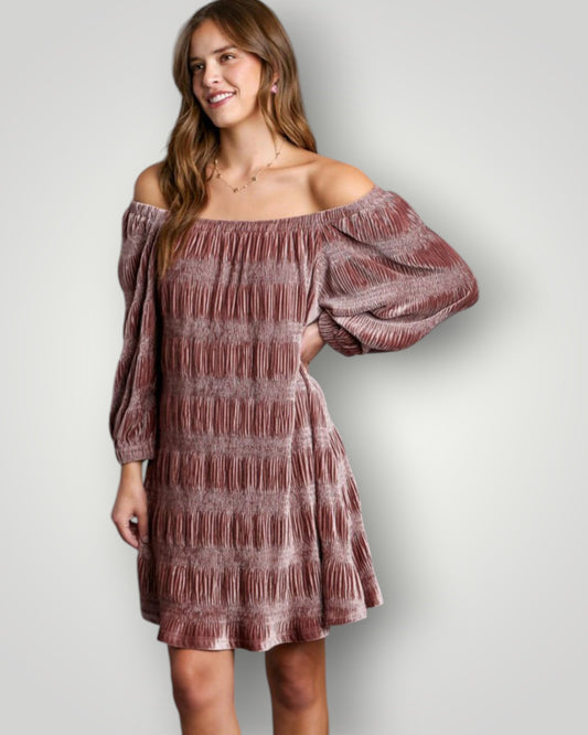 Woman wearing a off-shoulder dress with ruffled sleeves against a plain background