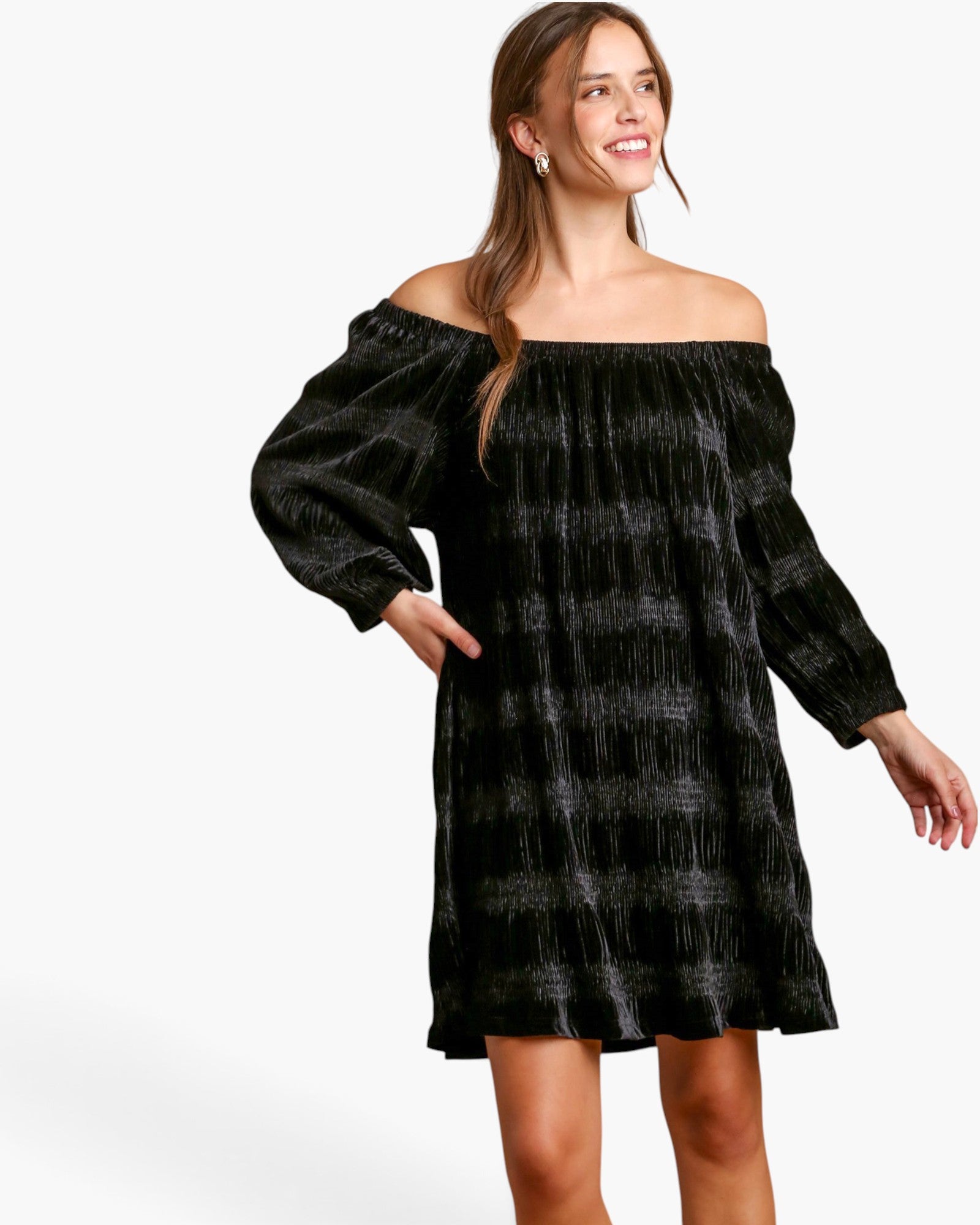 A woman modeling an off-the-shoulder black velvet dress with a subtle gray plaid pattern, set against a plain white studio background.