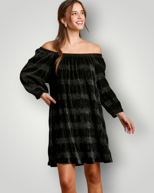 Woman wearing a black off-shoulder dress against a plain background