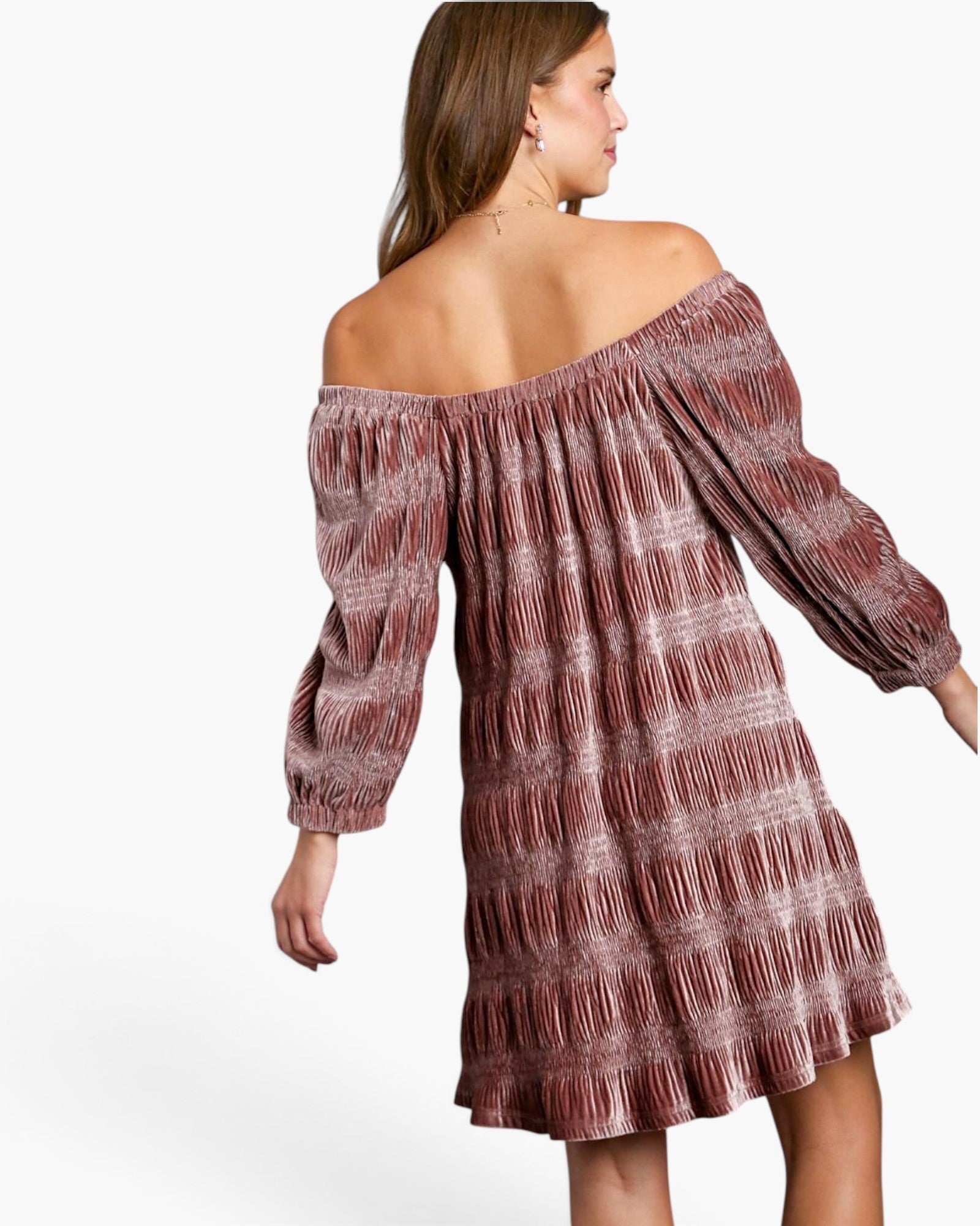 A woman wearing an off-the-shoulder, long-sleeve mini dress with a textured, pleated pattern in dusty rose and brown tones, shown from a three-quarters back view against a plain white background.