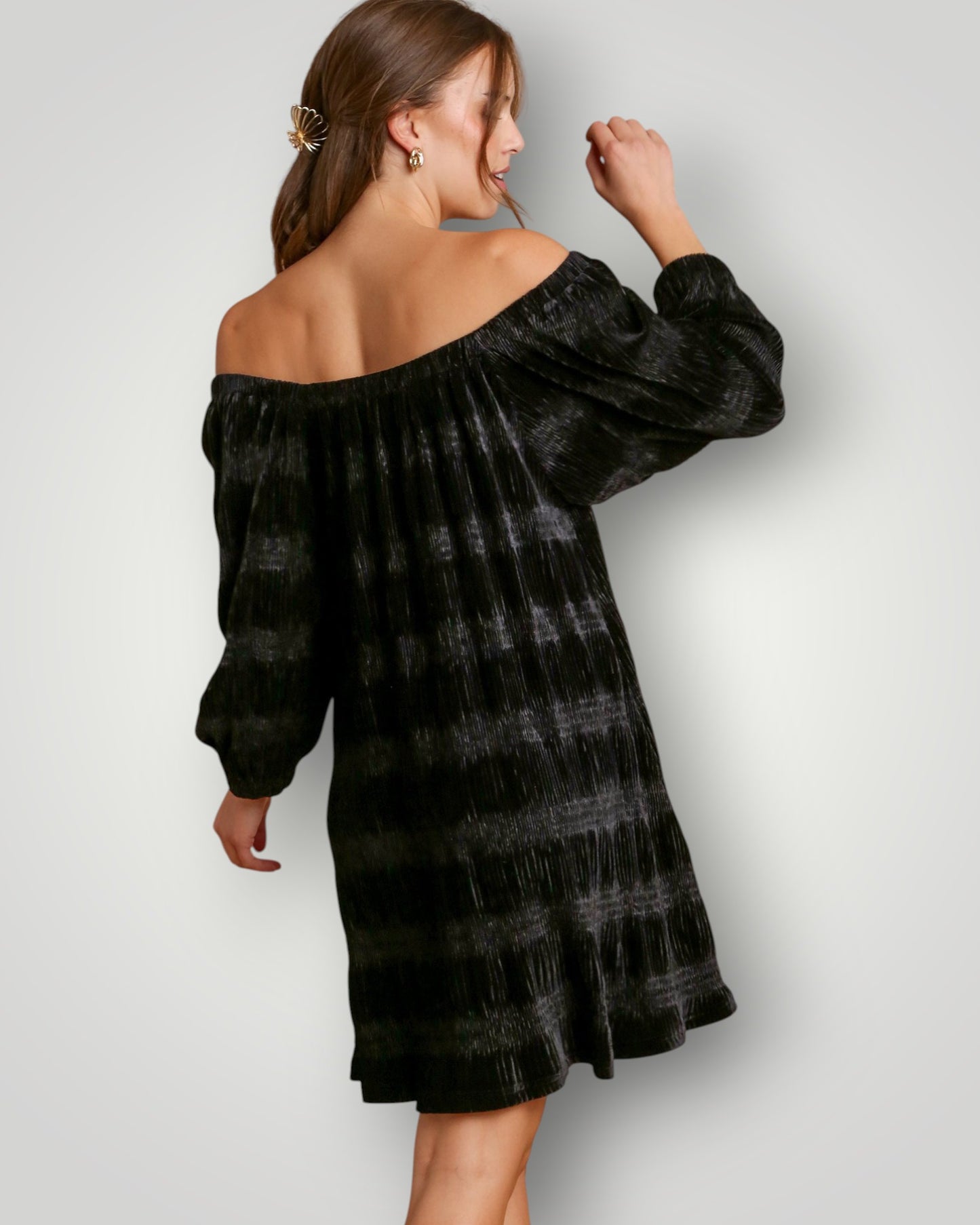 Woman wearing a black tie-dye off-shoulder dress against a white background