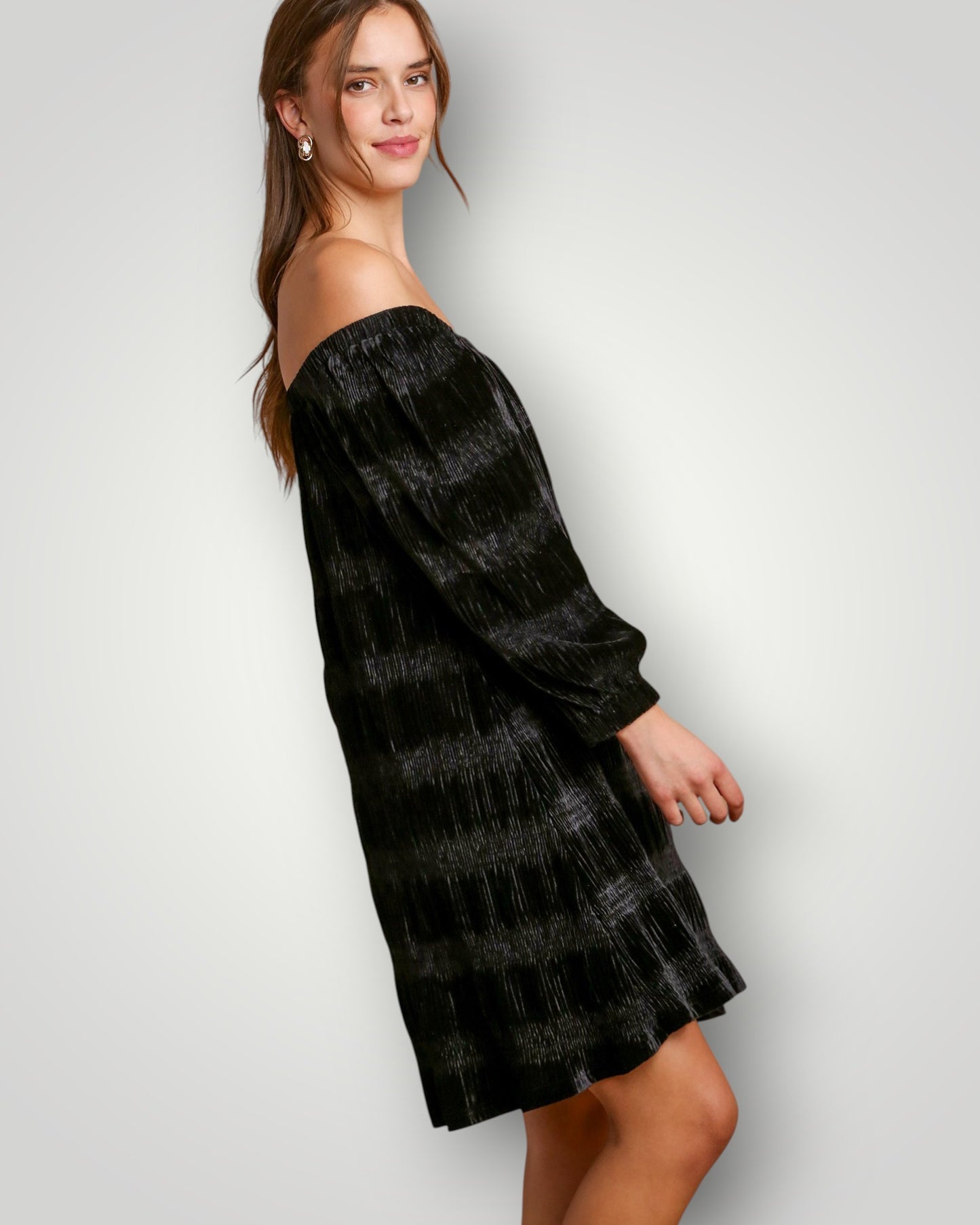 Woman wearing a black off-shoulder dress against a plain background