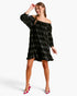 A woman modeling an off-the-shoulder black velvet mini dress with a subtle gray plaid pattern, paired with red high heels, against a plain white studio background.