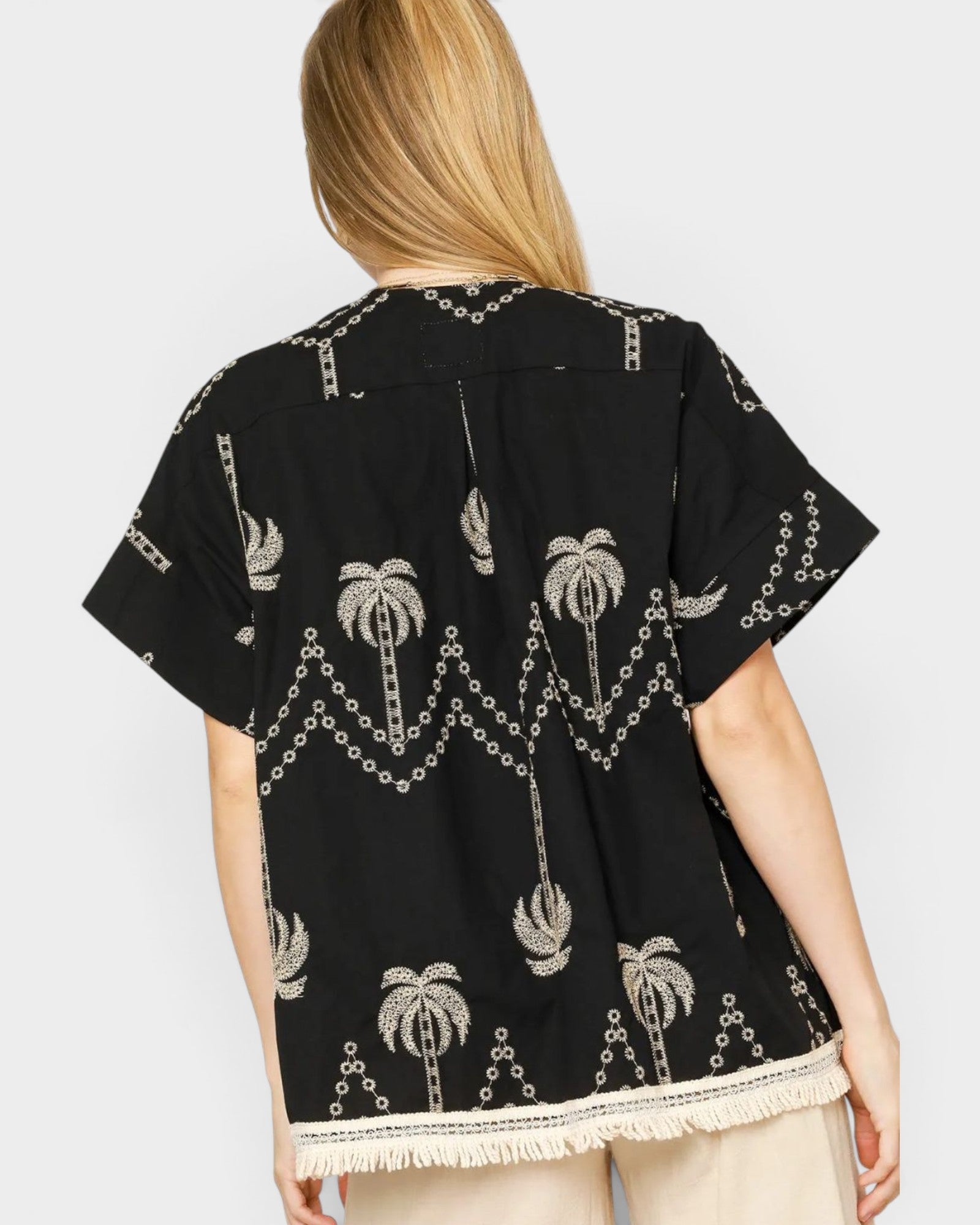Black embroidered shirt with palm tree design on a white background