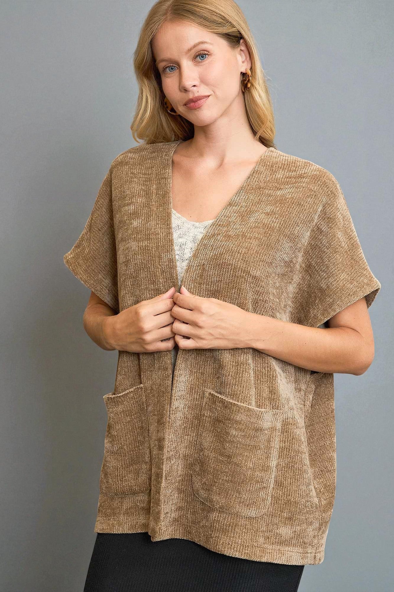 Woman wearing a brown textured cardigan against a gray background