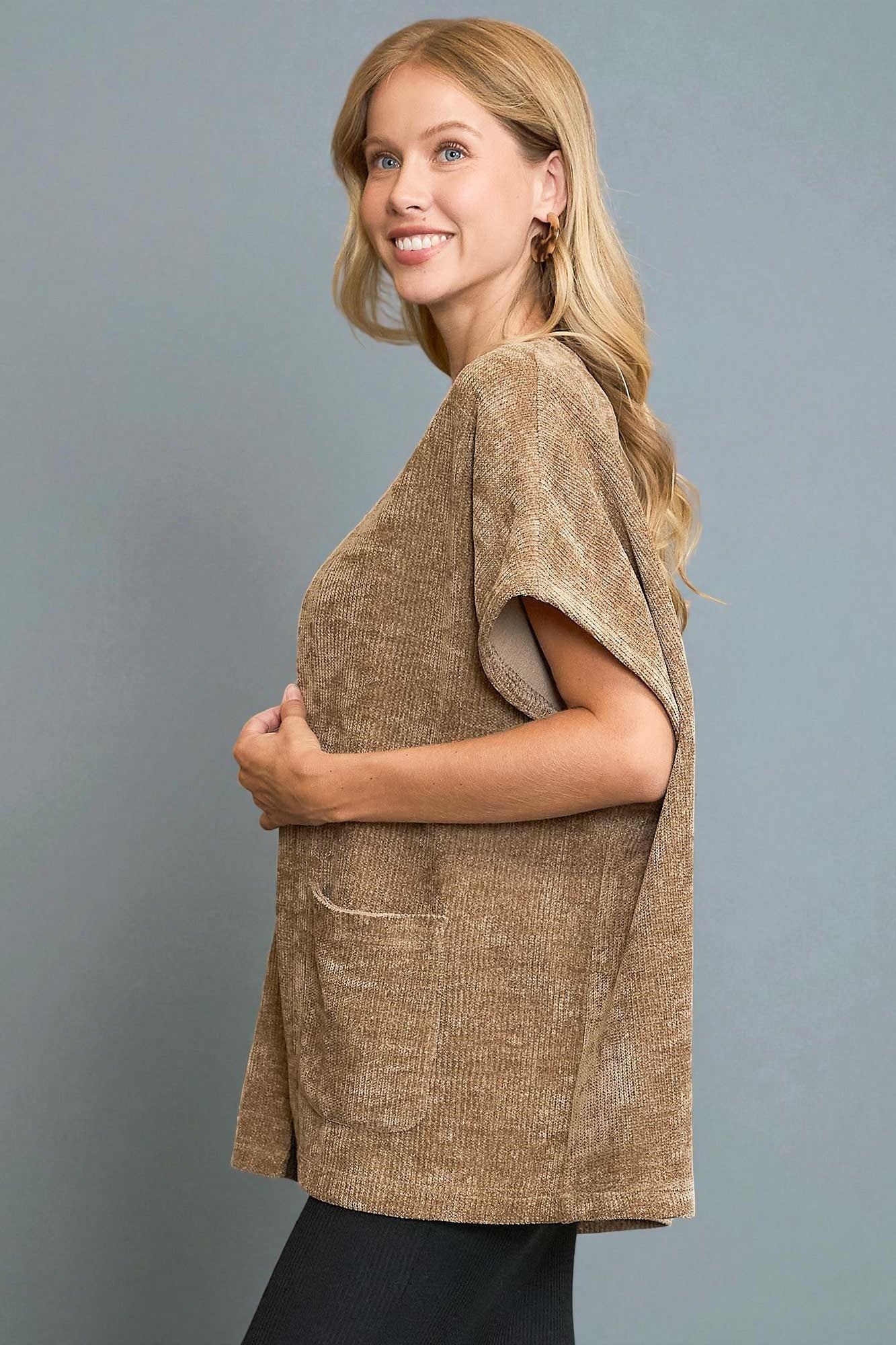 Woman wearing a brown textured top against a gray background
