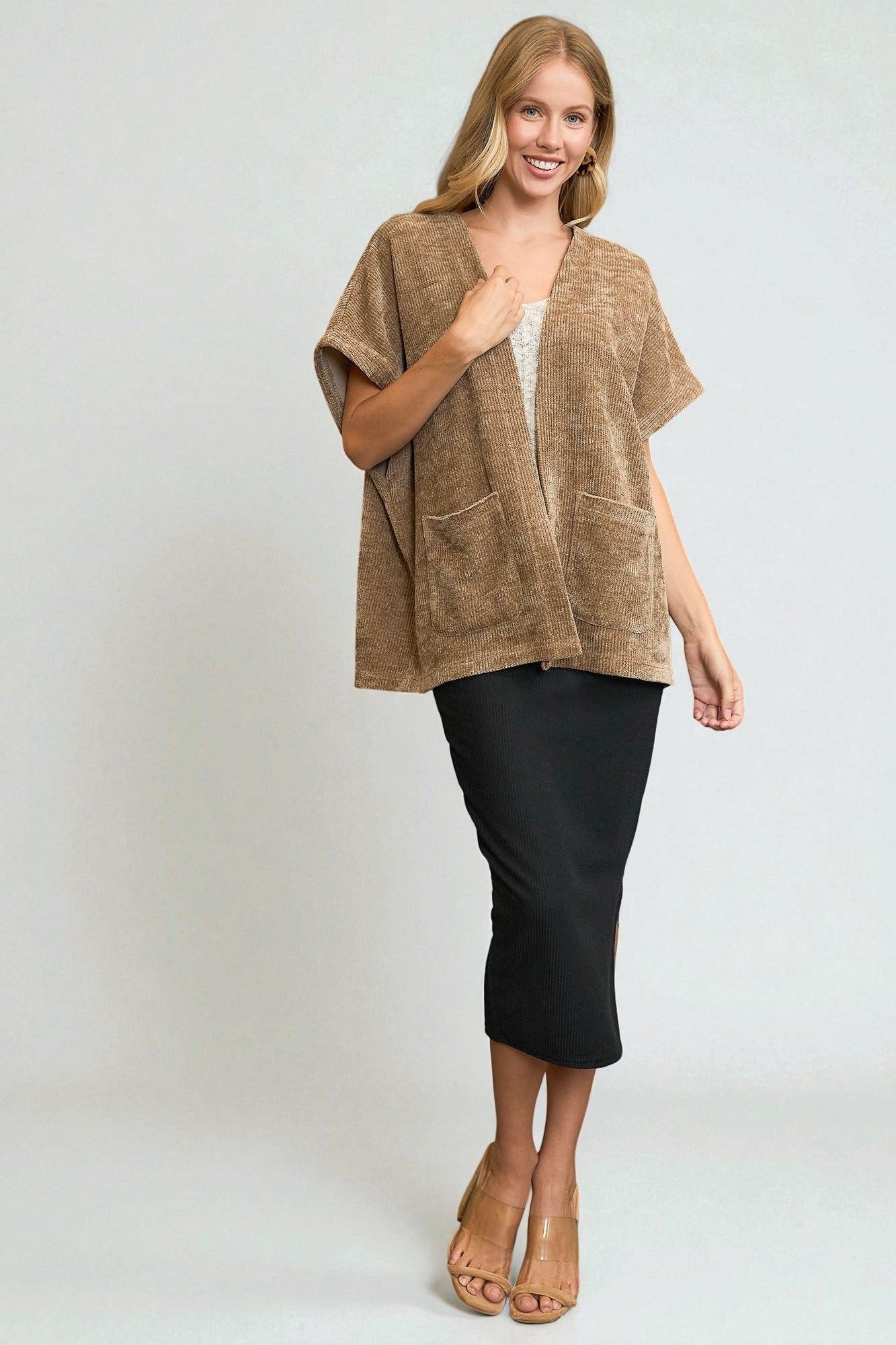 Woman wearing a brown short-sleeve top and black pants on a white background