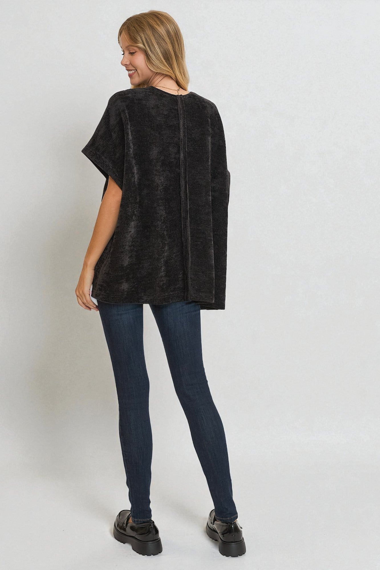 Woman wearing a black oversized sweater and dark jeans on a white background