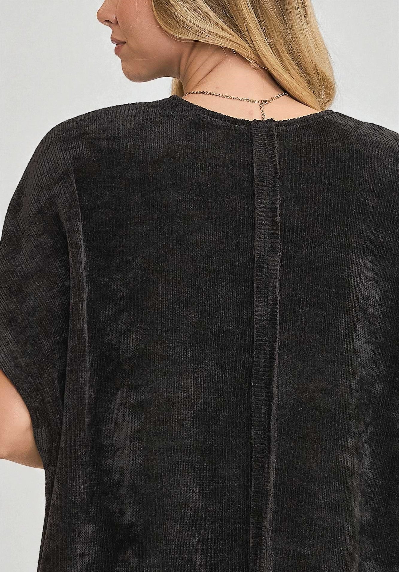 Black textured top worn by a person on a light gray background