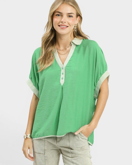 Woman wearing a green blouse with white trim on a white background