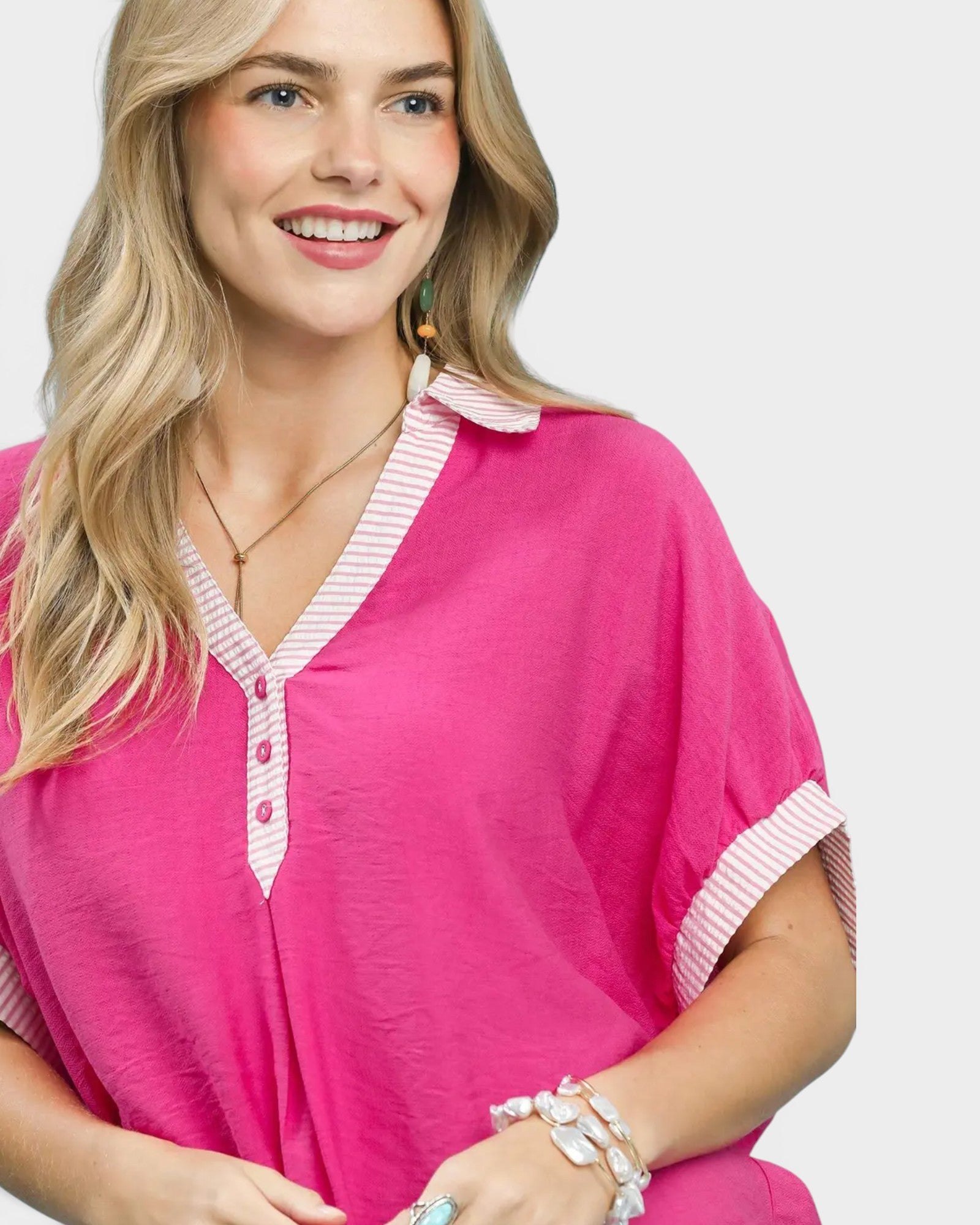 Woman wearing a pink outfit with white trim on a plain background