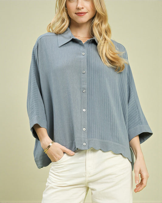 Woman wearing a blue striped shirt and white pants on a beige background