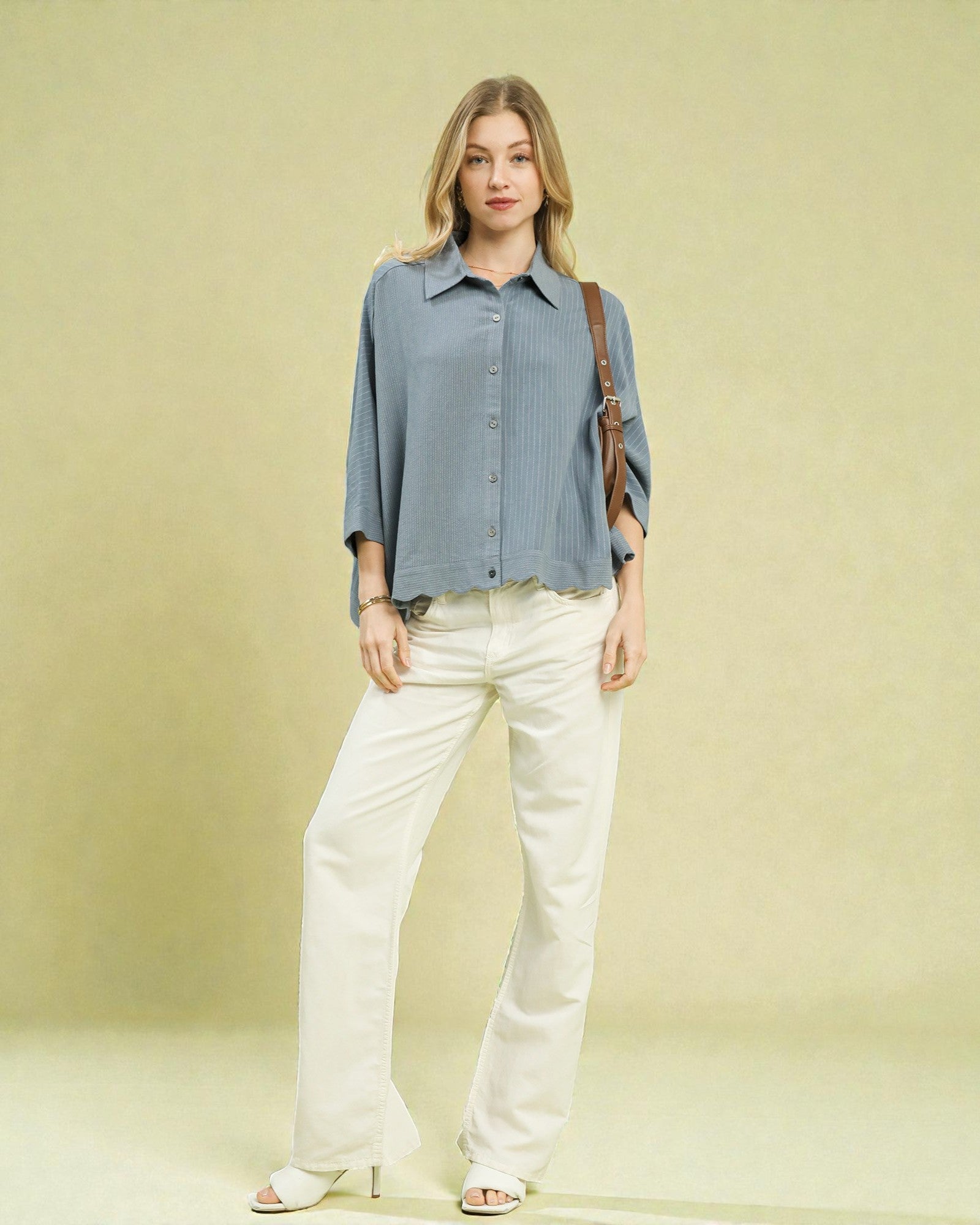 Woman wearing a blue shirt and white pants against a light green background
