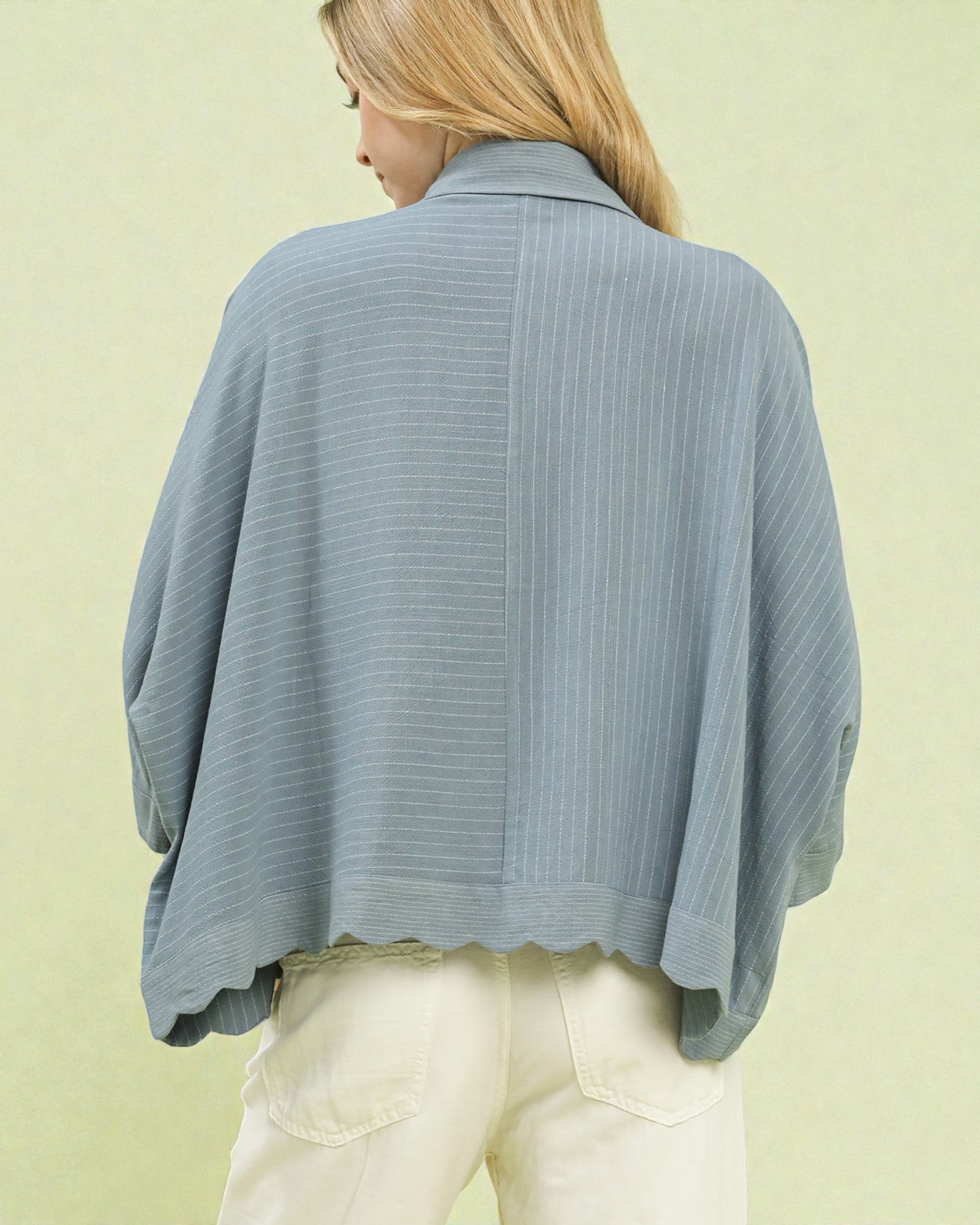 Woman wearing a light blue ribbed sweater against a light green background