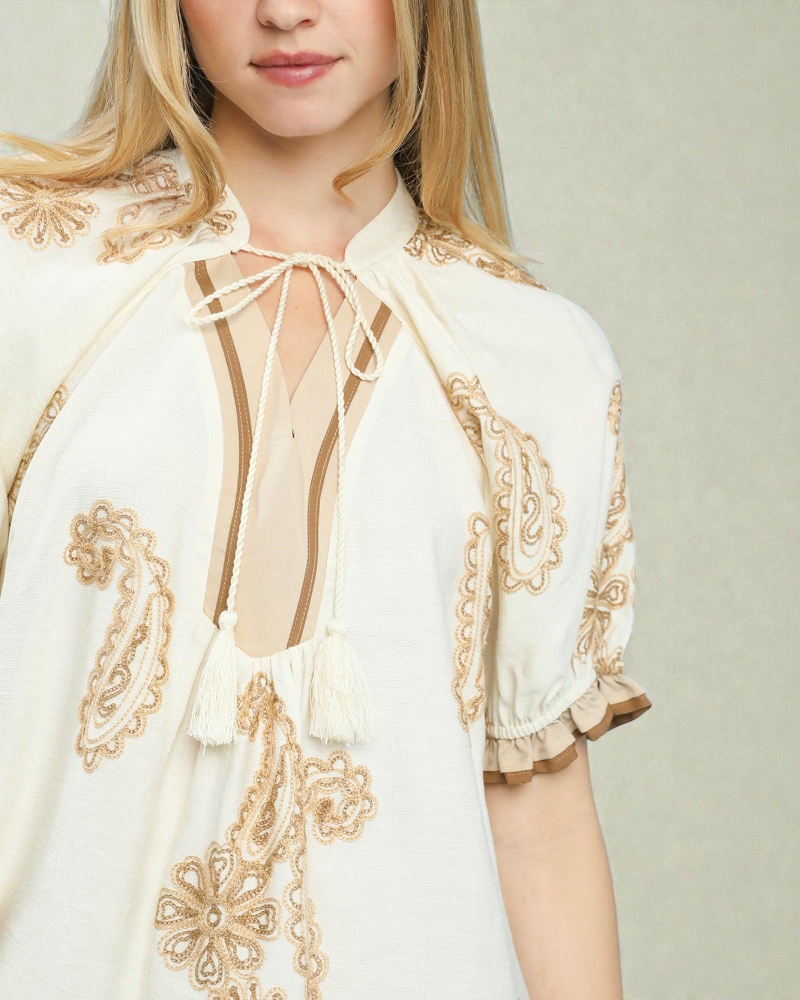 White blouse with gold embroidery on a plain background