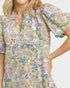 Woman wearing a colorful patterned shirt with a neutral background