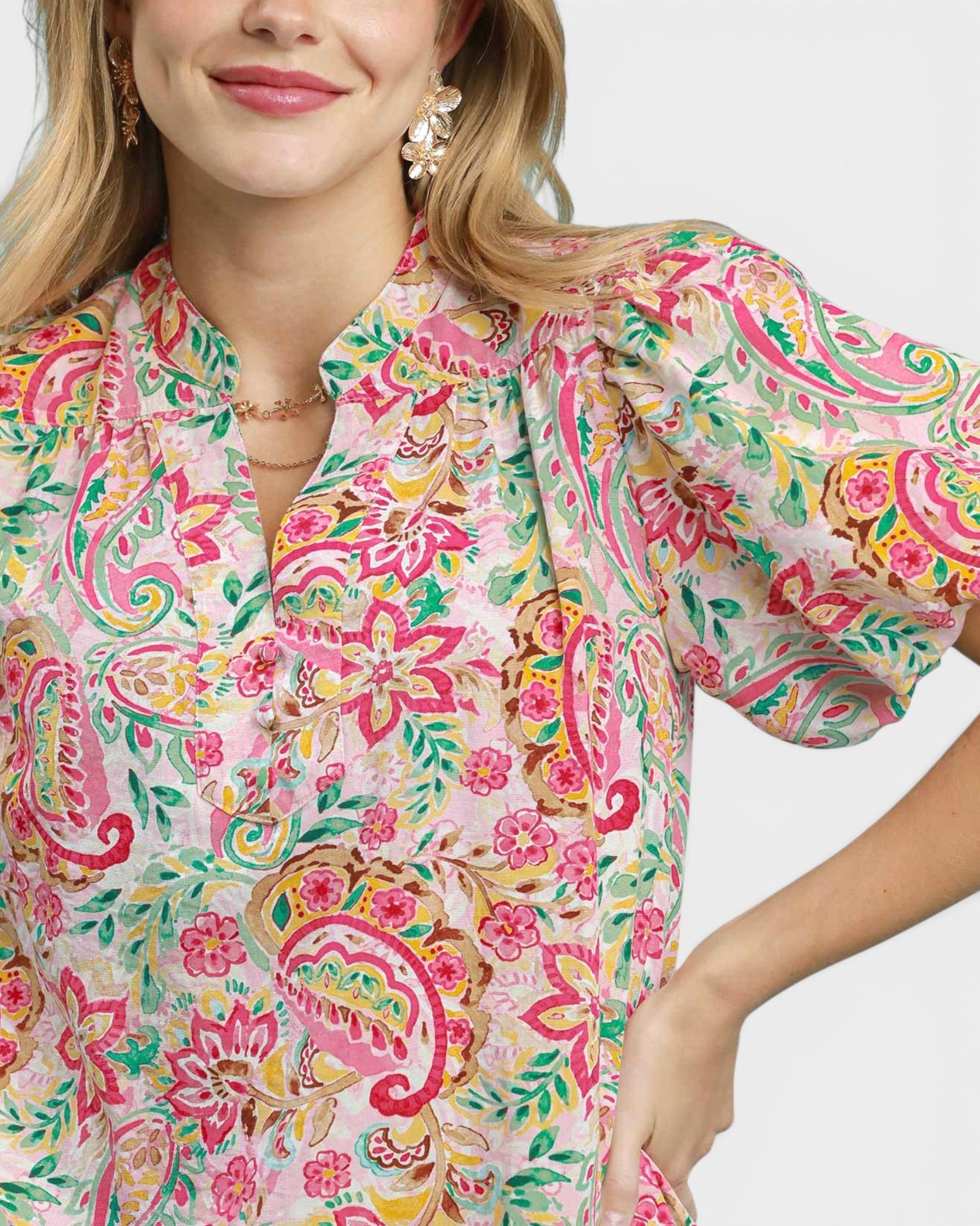 Woman wearing a colorful floral blouse with puff sleeves on a white background