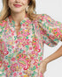 Woman wearing a colorful floral blouse with puff sleeves on a white background
