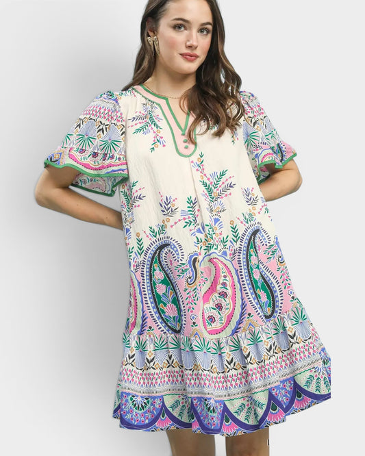 Woman wearing a colorful paisley dress against a white background