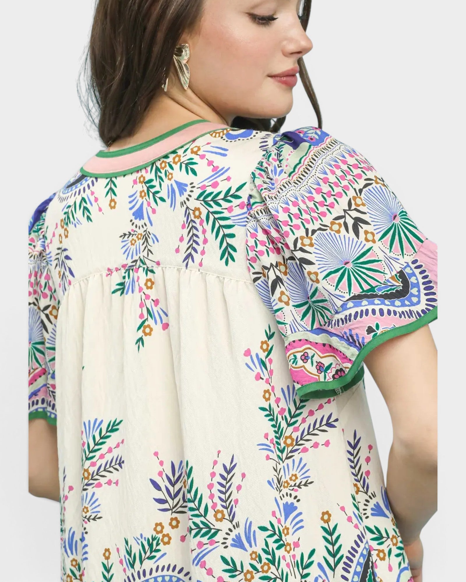 Woman wearing a colorful embroidered blouse with a neutral background