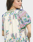 Woman wearing a colorful embroidered blouse with a neutral background