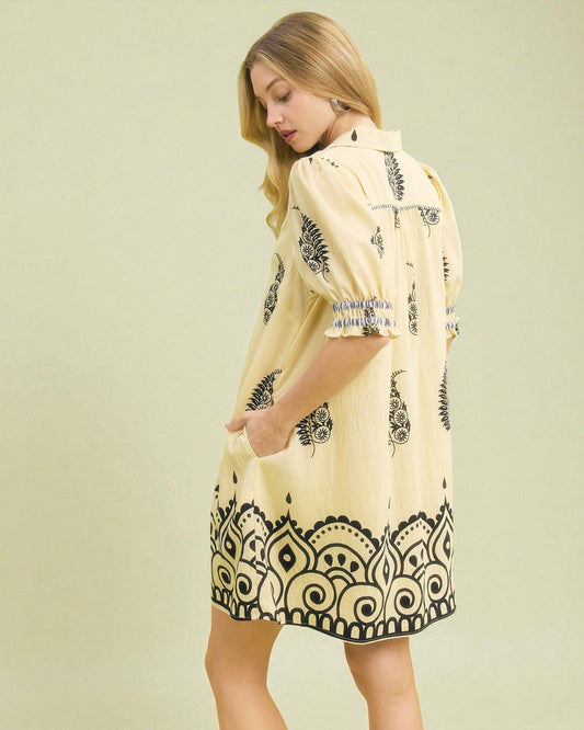 Woman wearing a yellow dress with black patterns on a light green background