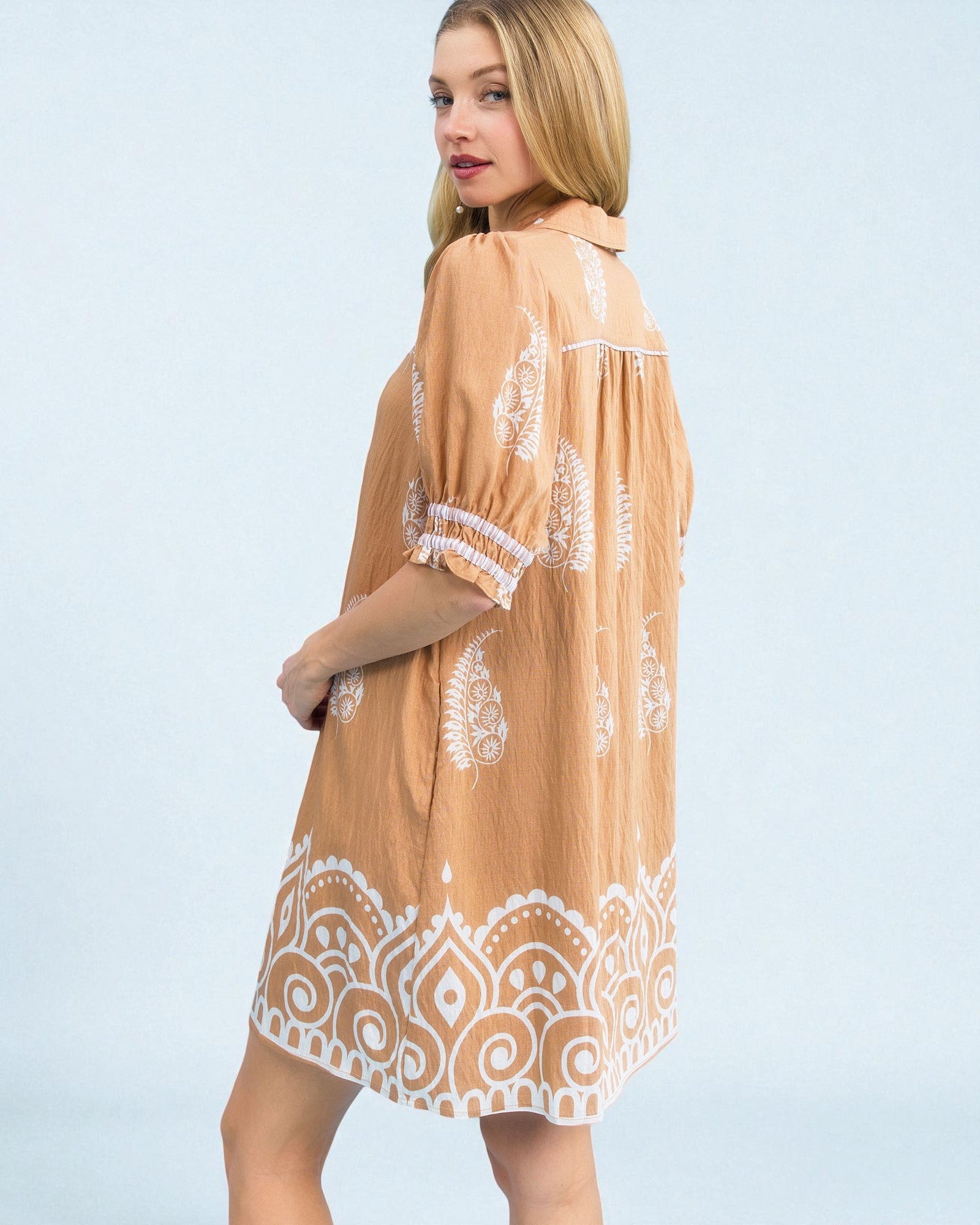 Woman wearing a beige dress with white lace details on a light blue background