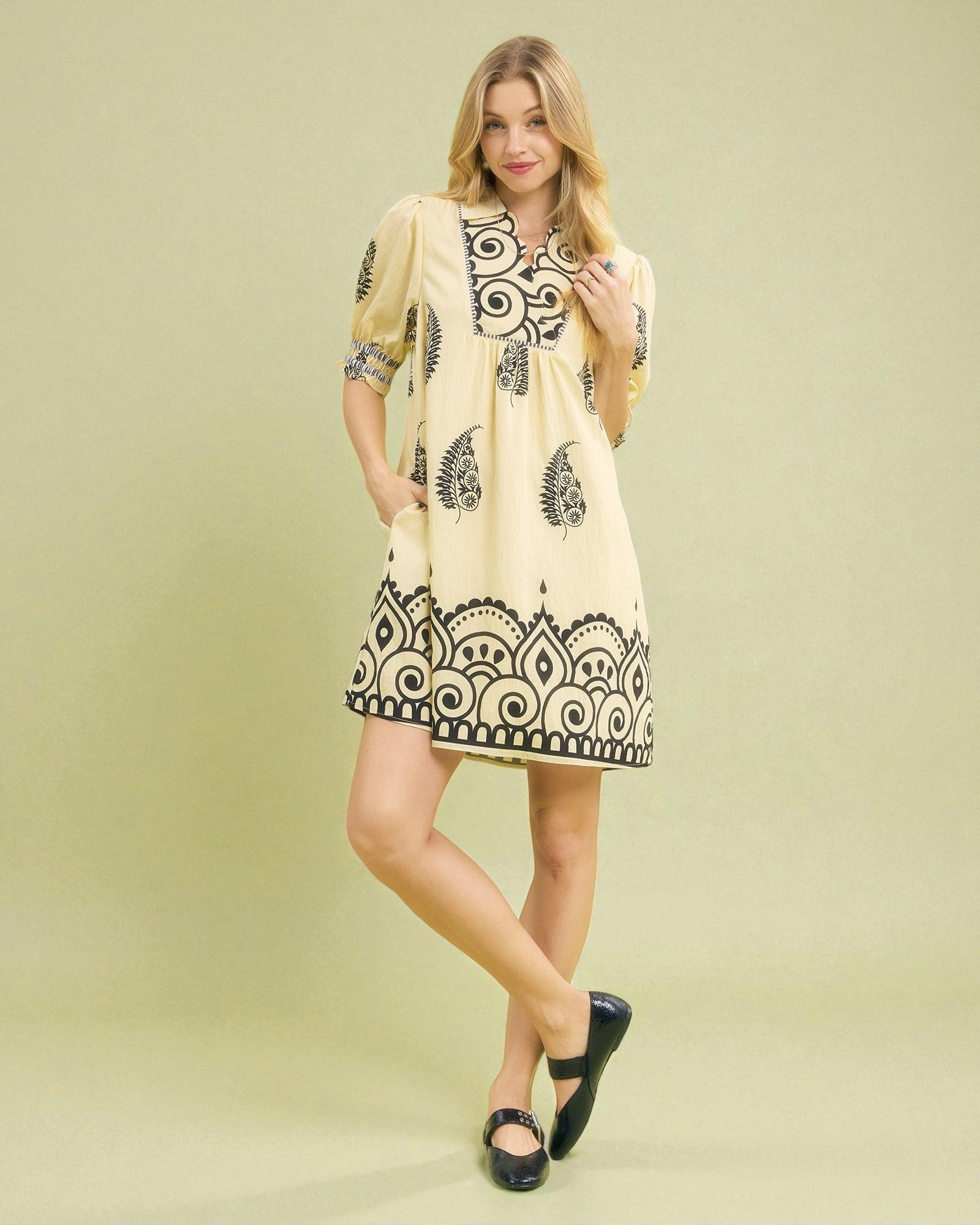 Woman wearing a beige dress with black patterns on a light green background