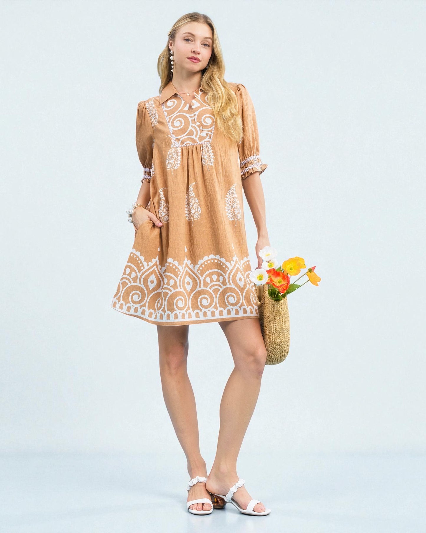 Woman wearing a beige dress with white lace details on a light blue background