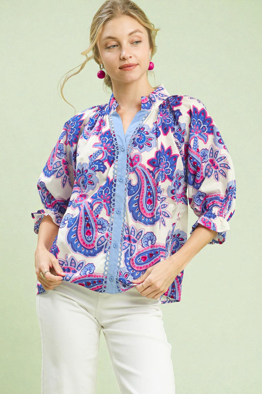 Woman wearing a colorful paisley shirt against a light green background