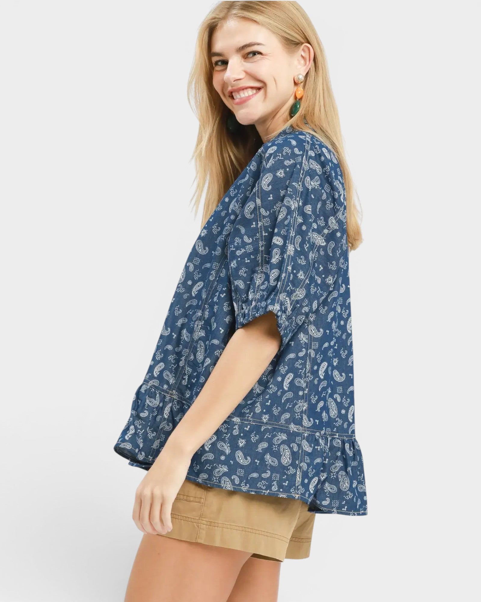 Woman wearing a blue patterned top and beige shorts on a white background