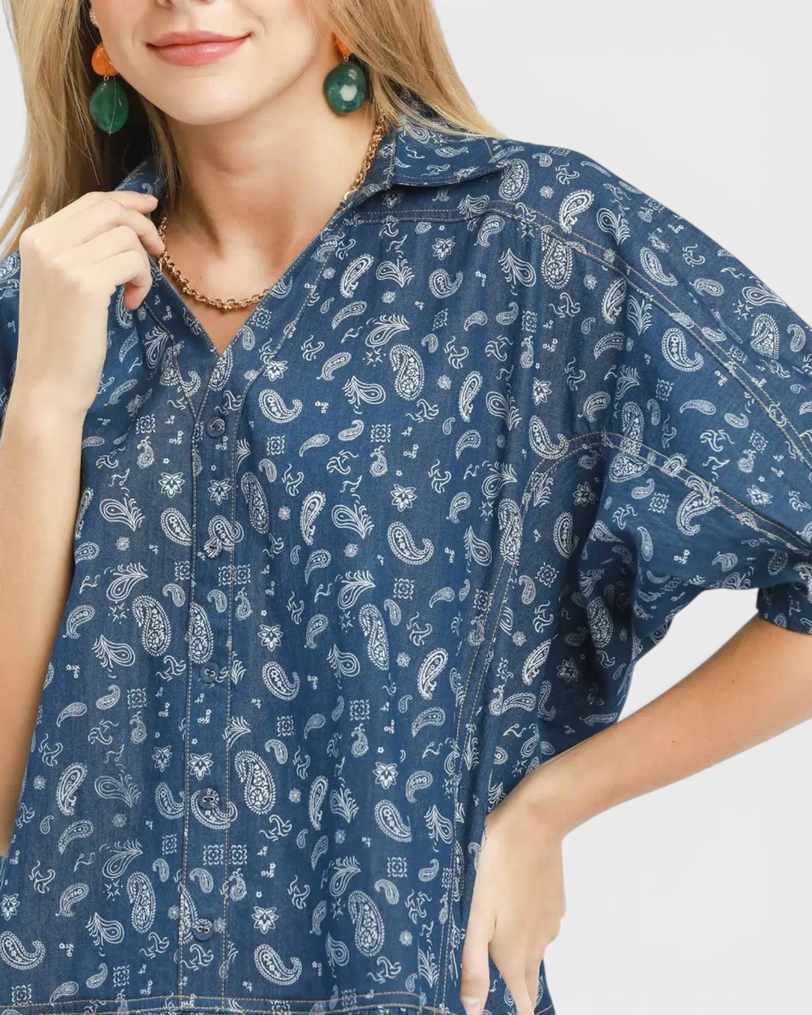 Woman wearing a blue paisley patterned shirt on a white background